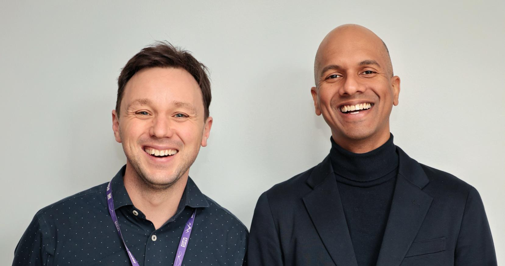two researchers are standing next to each other, smiling into the camera