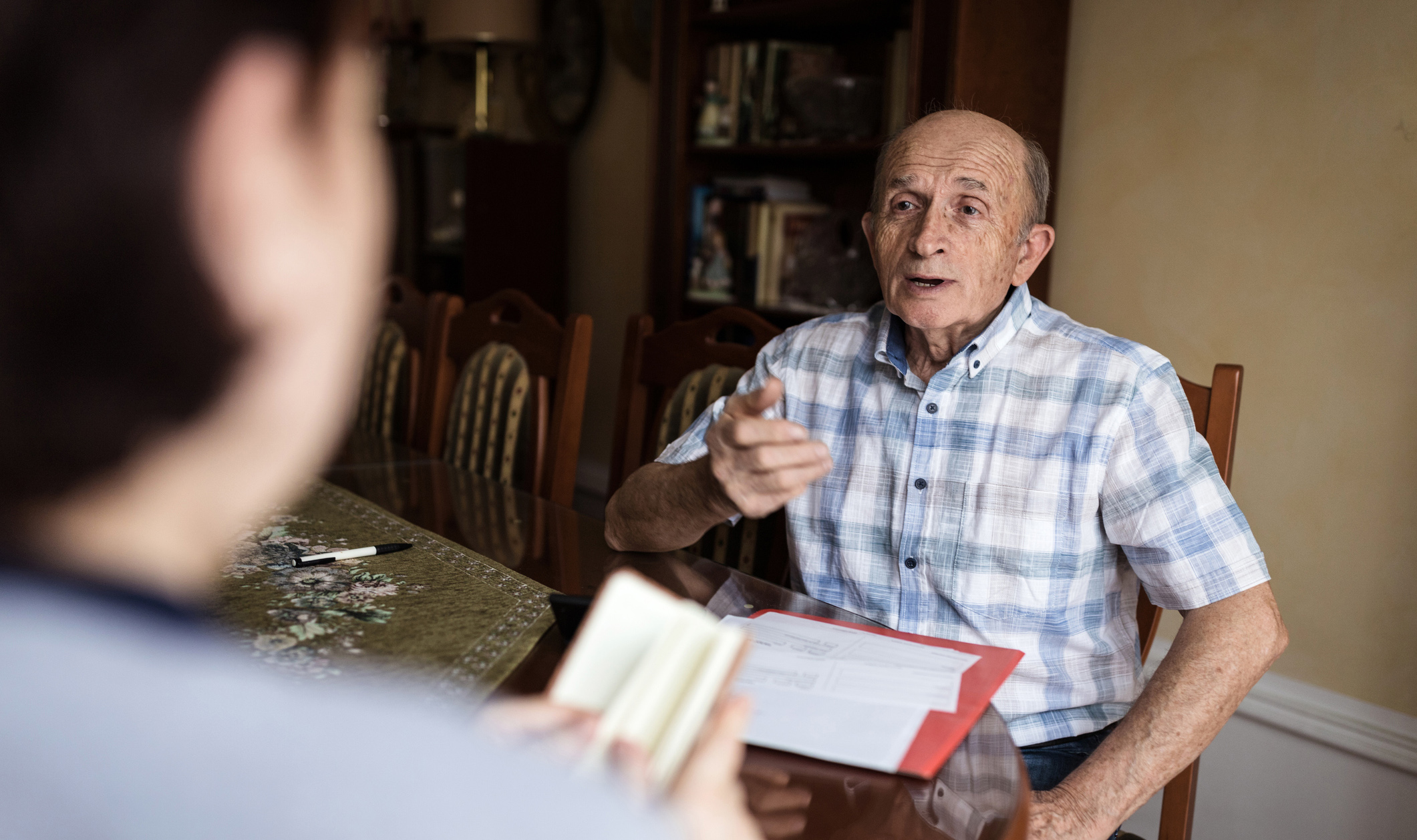 Senior man talking to his representative while holding documents on the table