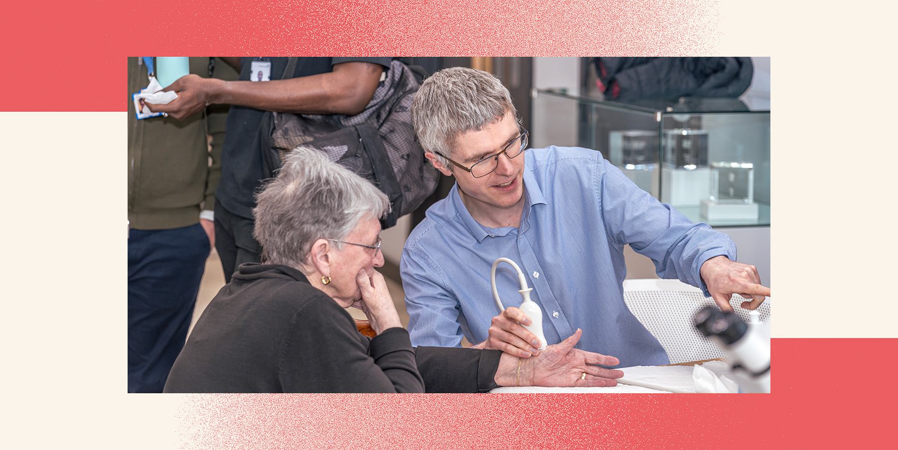The awarded researcher sits with a grey haired woman scanning her wrist.