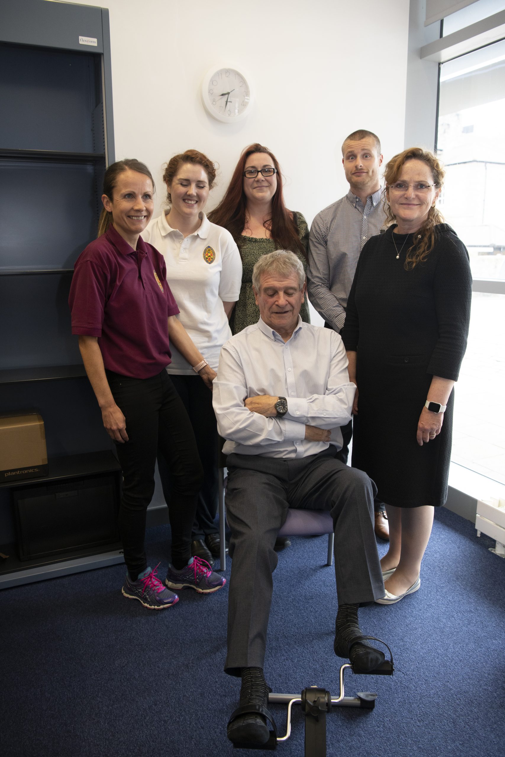 A group of researchers with a patient. All looking towards the camera.