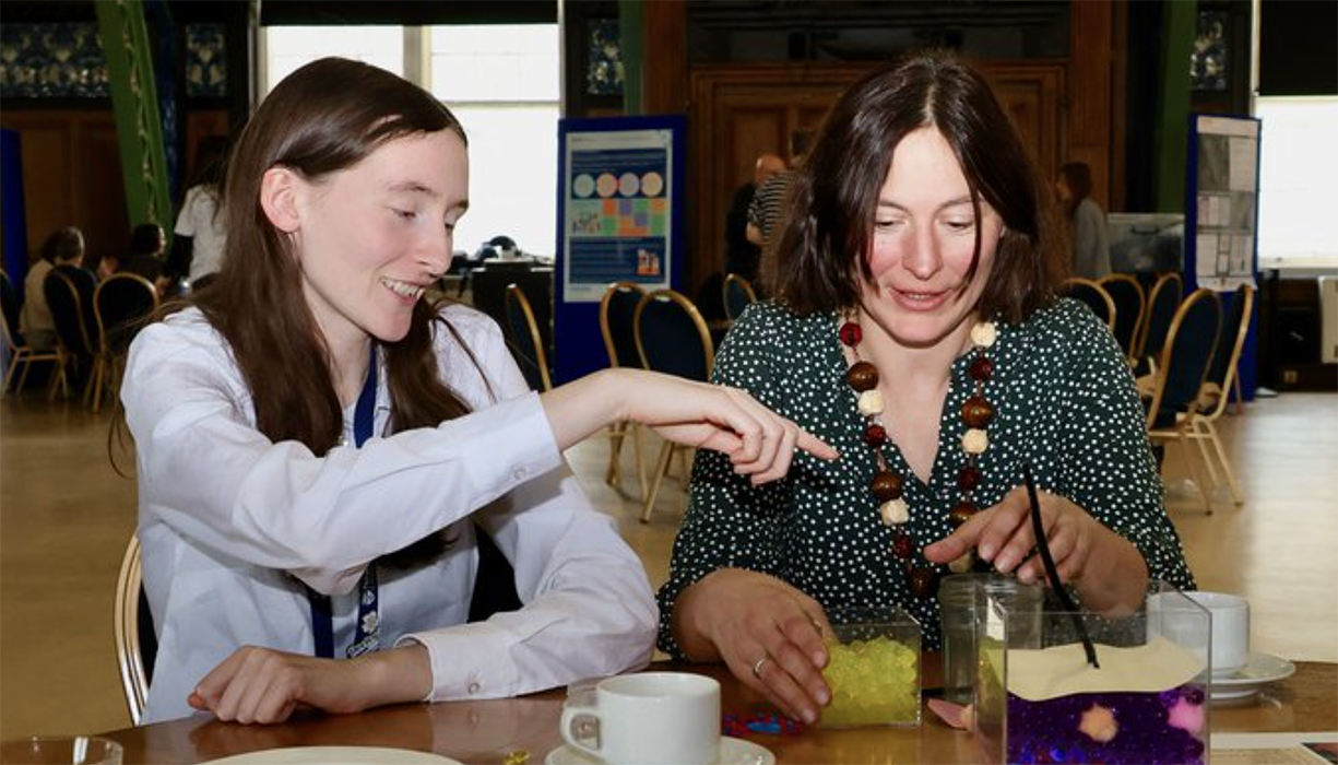 two people are sitting at a table and doing an experiment 