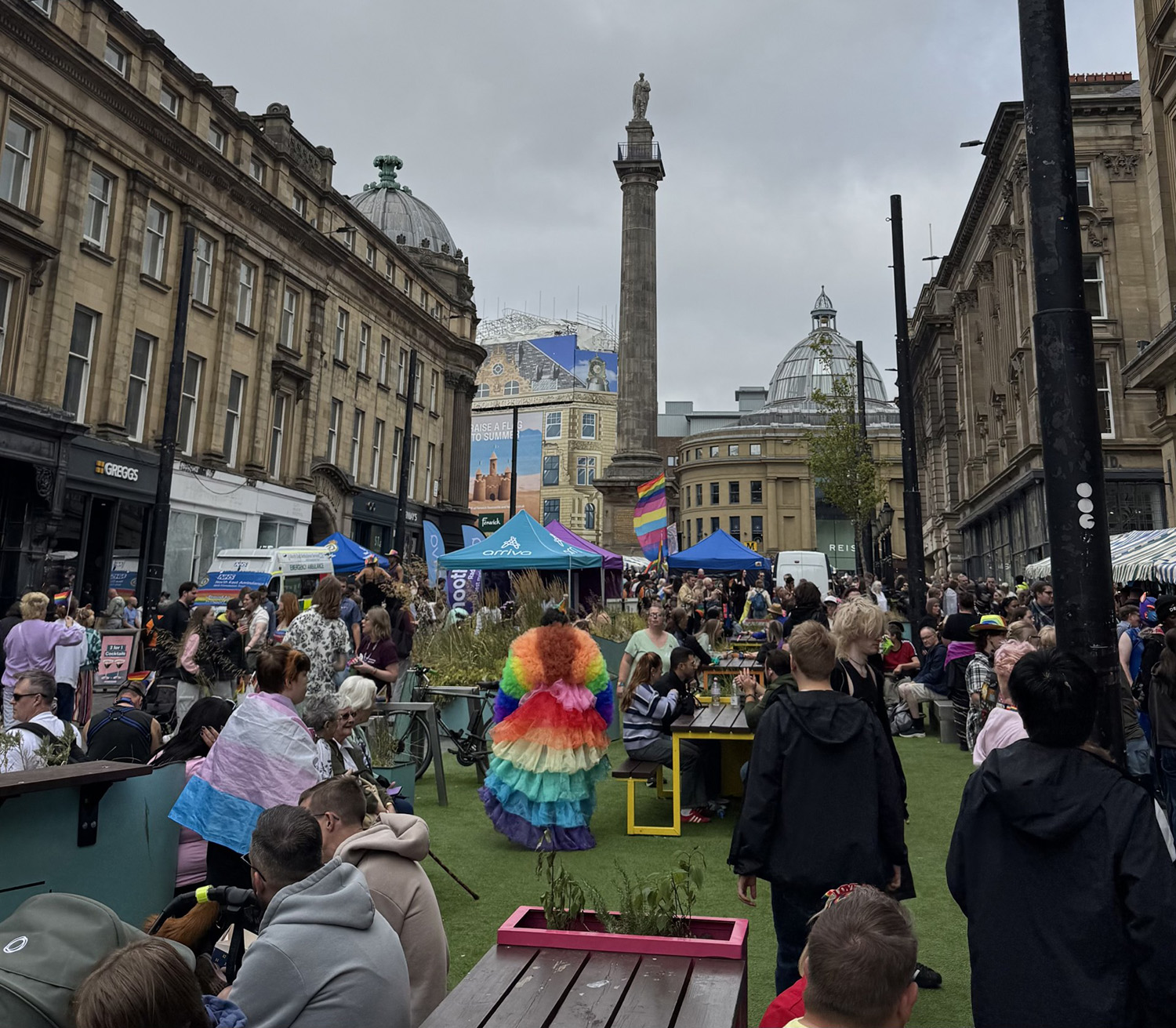 sNewcastle city centre with a bunch of people around. In the middle is a person in a rainbow dress