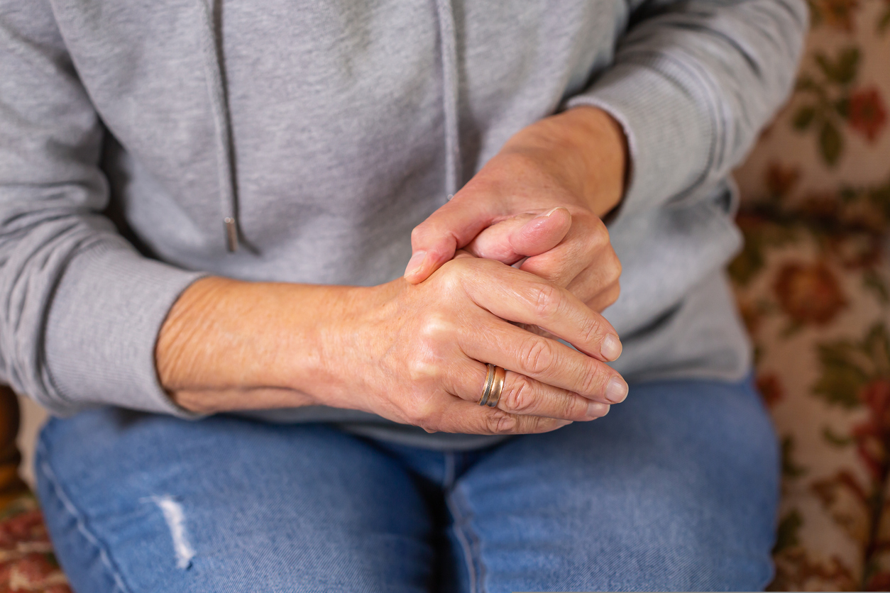 Senior woman suffering from hand and finger joint pain, and holding her right thumb with her left hand.