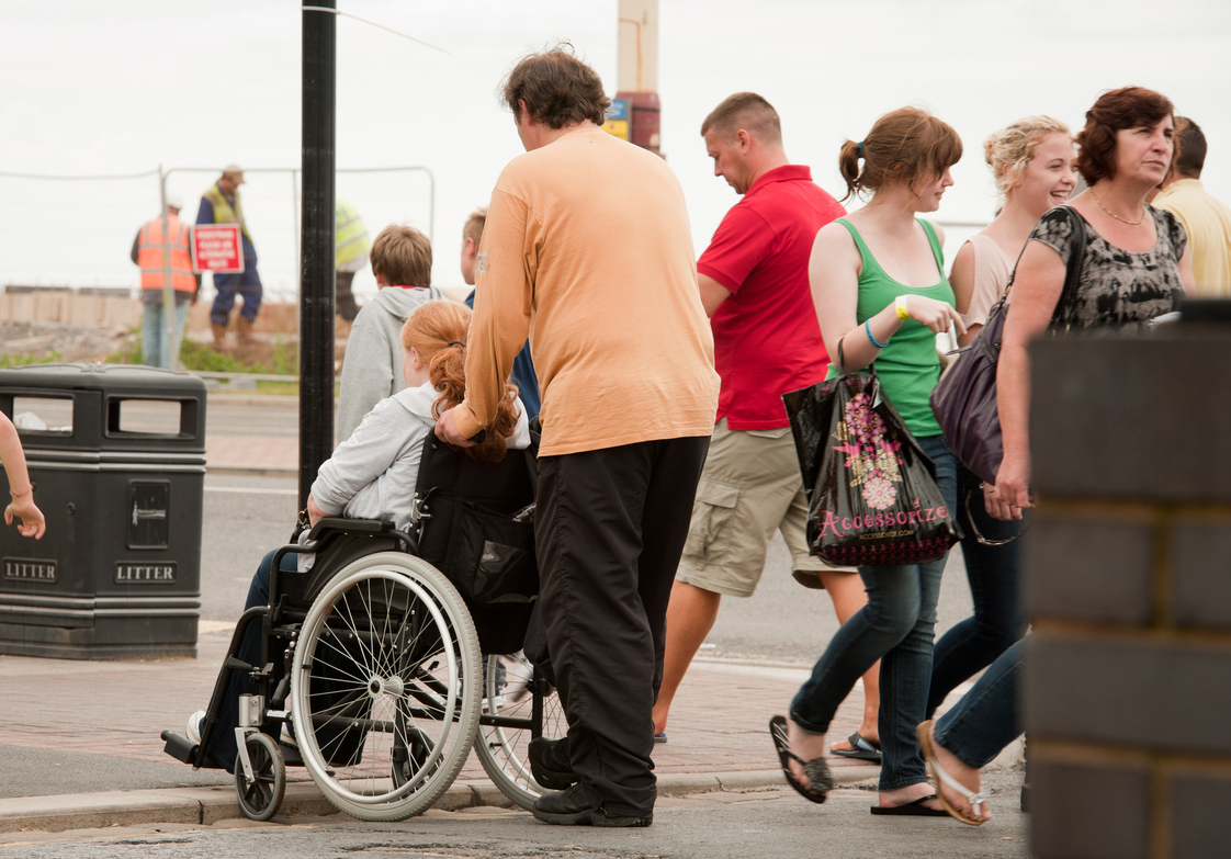 A man pushing a wheelchair in a crowd